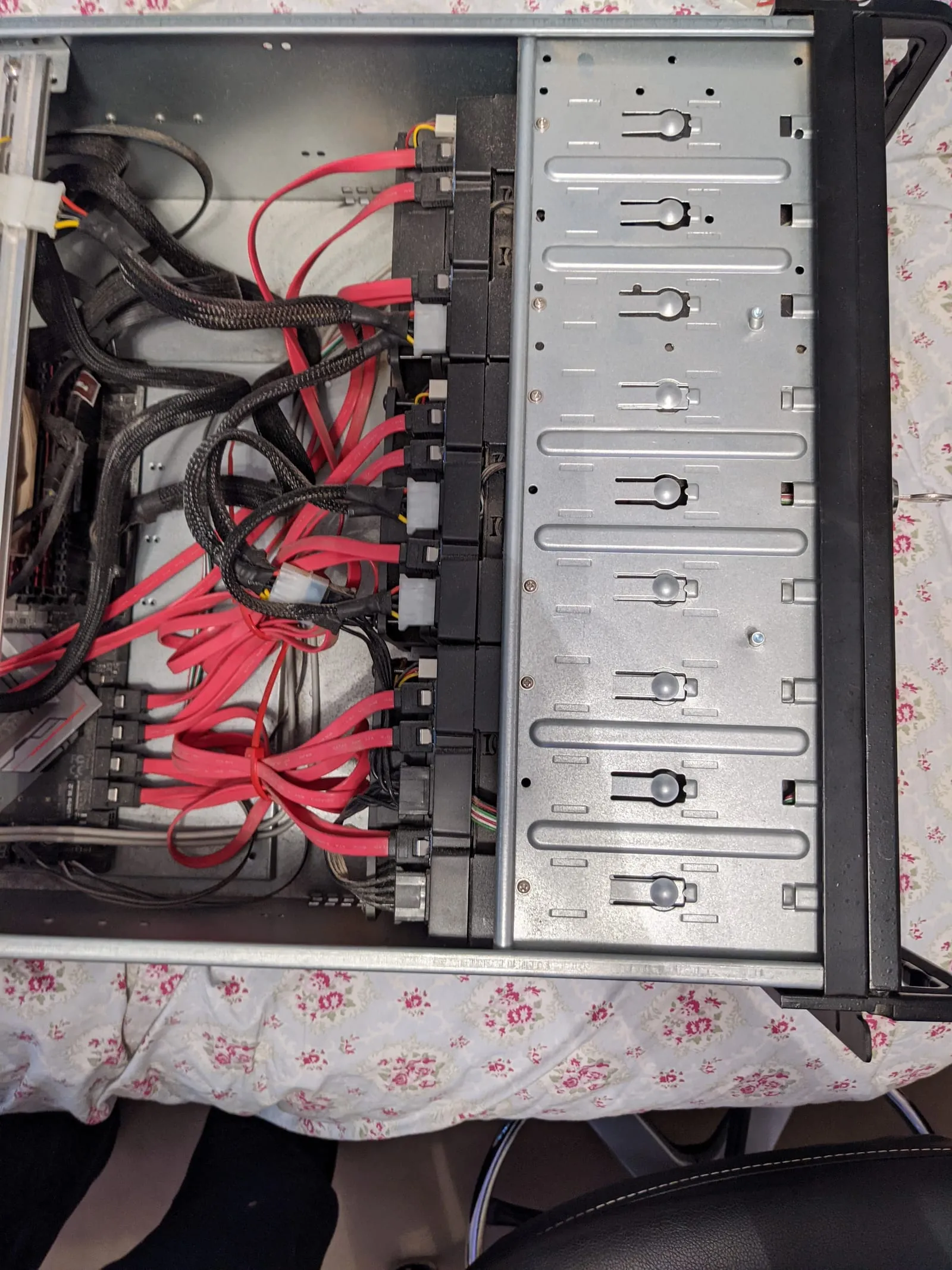 The inside of an open storage chassis showing a row of drive bays and a dense tangle of red SATA cables