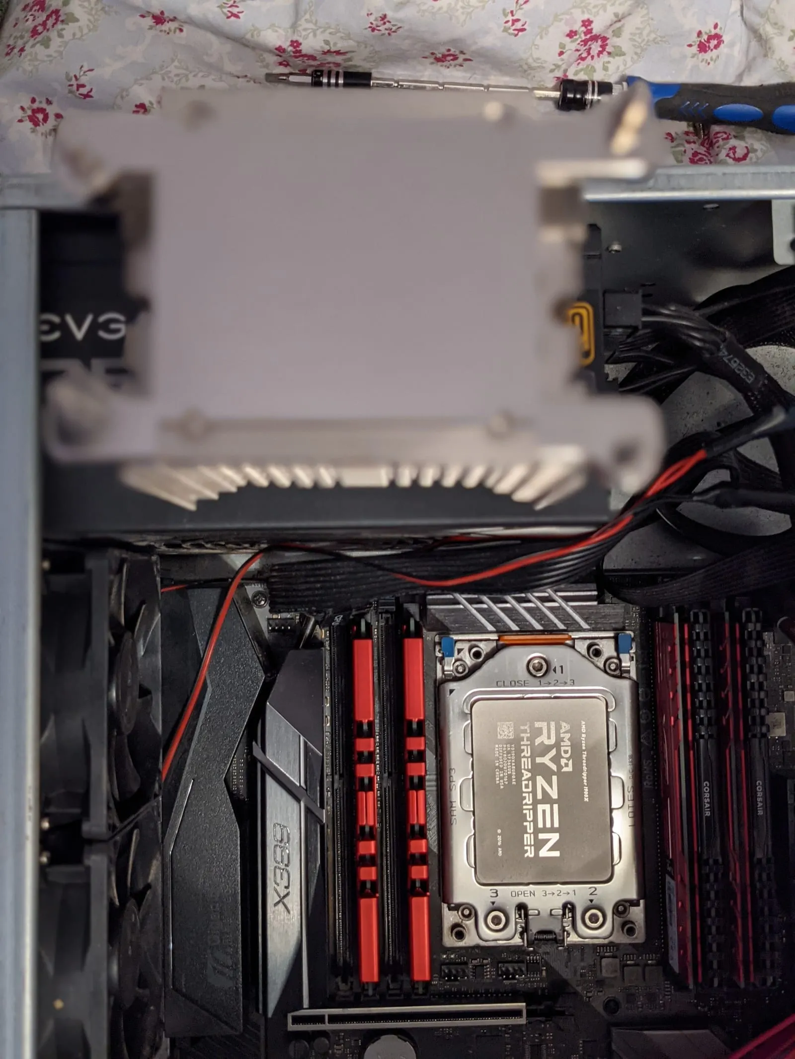 An AMD Ryzen Threadripper CPU seated in an ASRock X399 motherboard socket, next to red memory sticks and a Noctua cooler